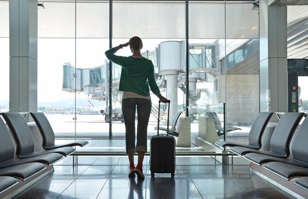 空港にて飛行機を眺める旅立ち前の女性