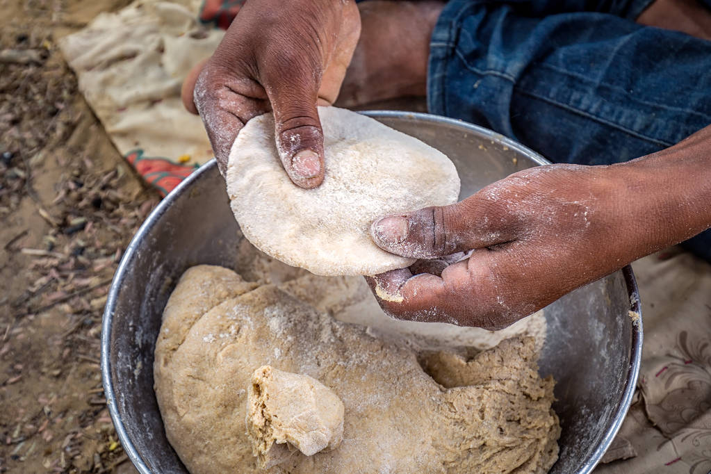 Kneading indian naan bread dough in metal bowl at Jaisalmer desert, India.