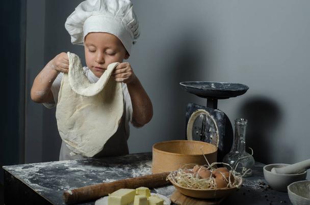Boy with chef hat preparing dough - kneading and stretching